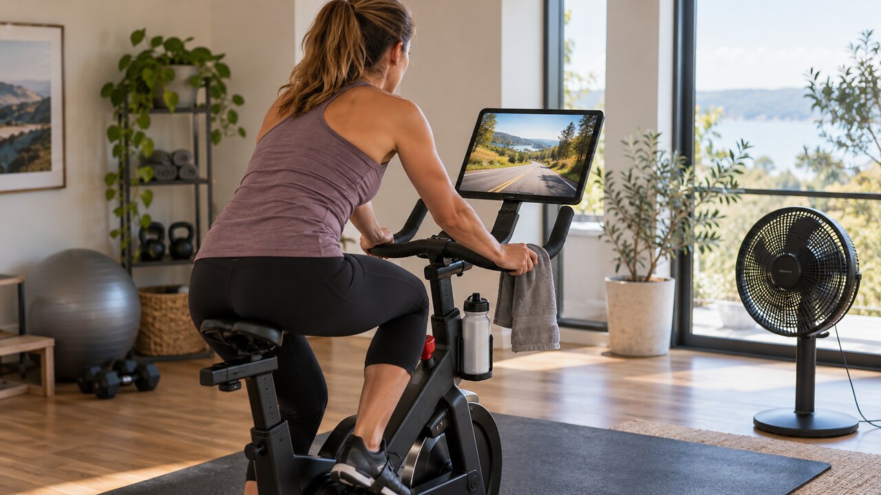Fietser op een indoor fiets met een tablet en een illustratief virtueel weglandschap